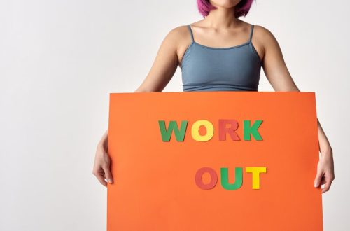 Woman with short hair holding a vibrant 'Work Out' sign on a white background.